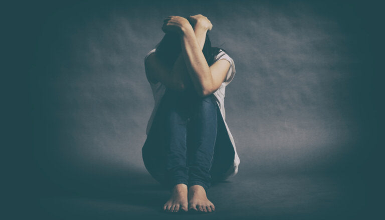 Una persona en el piso, cubriendo su rostro con sus brazos