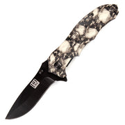 Navaja plegable metalica con hoja negra, clip para cinturon y empunadura con motivo de calaveras