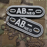 Placas identificativas negras de plástico marcadas AB- (negativo), dos chapas en una cadena