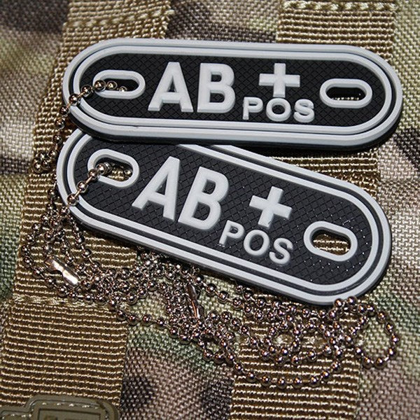 Placas identificativas negras de plástico marcadas AB- (negativo), dos chapas en una cadena