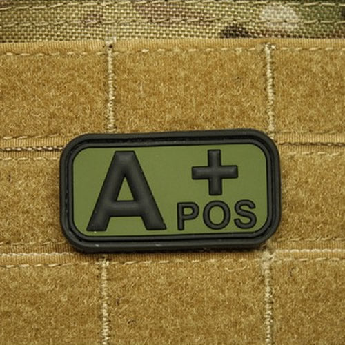 Parche plástico verde 'KREV A POS' con respaldo de velcro, 5 x 2,5 cm
