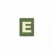 Parche identificativo 'E' verde con velcro, plástico y fosforescente (brilla en la oscuridad)