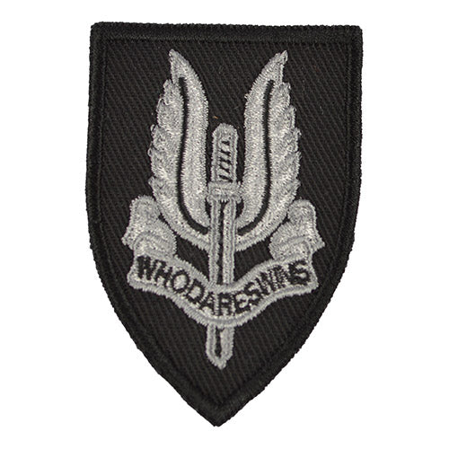 Parche SAS plateado sobre fondo negro con espada alada y cinta 'WHO DARES WINS', aprox. 6,5×5 cm